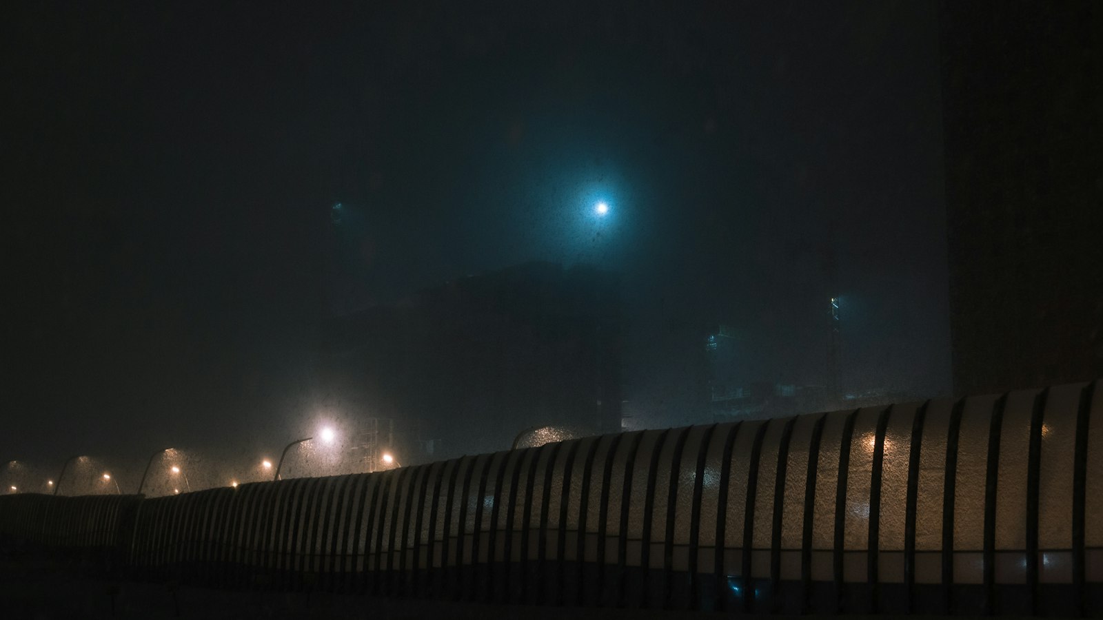 Foggy night with glowing streetlights and distant moon