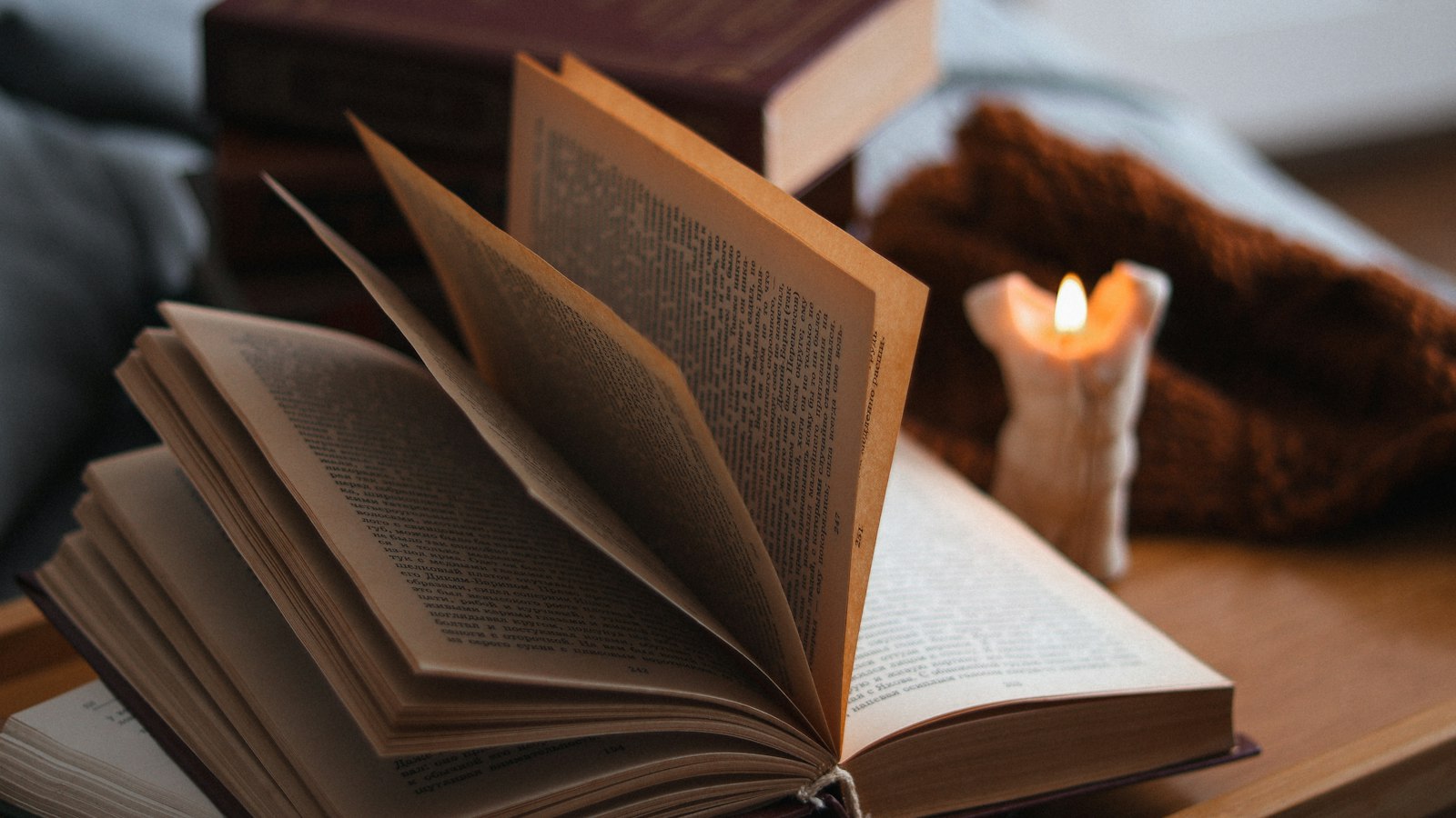 an open book sitting on top of a table next to a candle