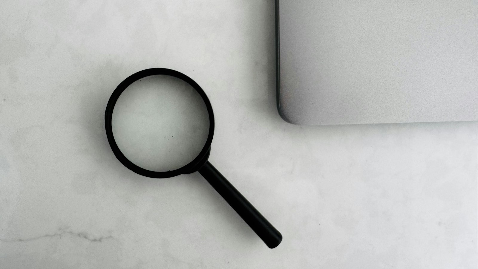 Magnifying glass sits near a laptop on a table