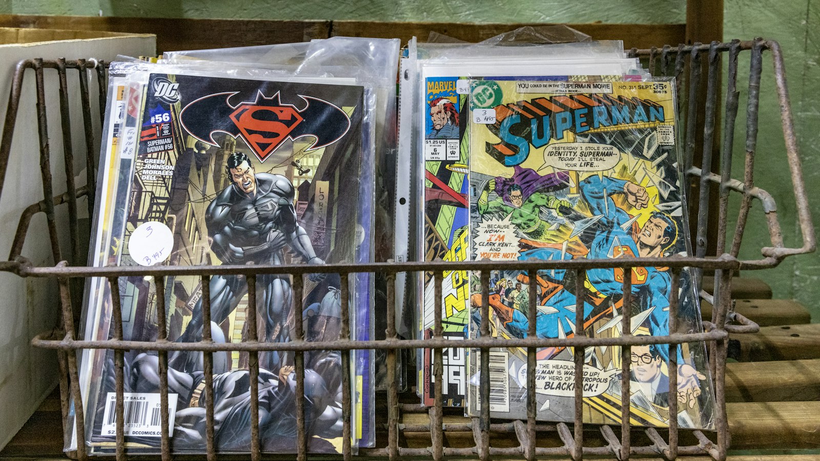 a metal basket filled with comic books on top of a table